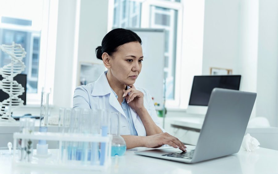 Researcher in lab sourcing samples using laptop